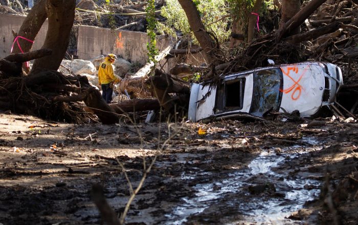 A car is overturned and a neighborhood overrun with mud as first responders and soldiers from the 315th Vertical Construction Company, California Army National Guard, work to clear debris, Jan. 13, 2018, in Montecito, California.