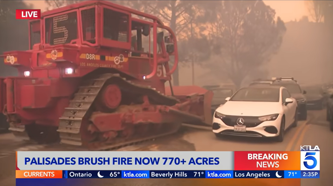 screencapture from news coverage showing red LA County fire bull dozer moving cars abondoned during fire evacuation